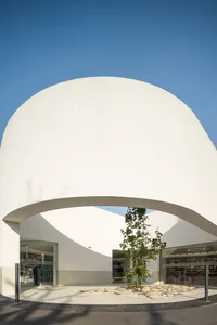 Modern white concrete public library entry with a curved archway.