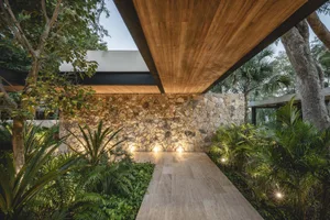 Modern patio with stone walls and floors surrounded by lush greenery and trees