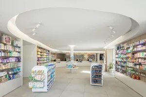 A modern retail space with white concrete flooring, glass display cases, and metal shelves.