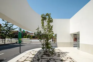 A modern retail storefront with a concrete facade lined by a cracked cobblestone sidewalk and a large white rectangular canop