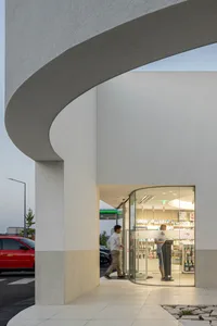 Modern retail storefront with curved concrete entrance and glass door.