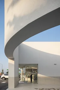 Modern retail storefront with concrete facade and curved entrance.