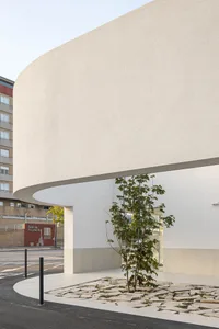 A modern urban space featuring concrete elements with a tree and mosaic tile entryway.