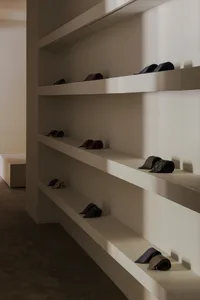 A minimalist furniture display featuring concrete shelves and neatly folded neckties.