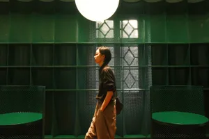 A person walking in a modern interior space with textured green walls