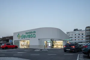Modern retail storefront with concrete facade, featuring a pharmacy logo and interior view.