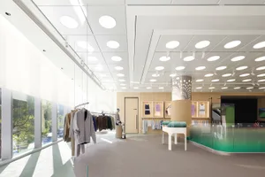 A minimalist interior design of a white concrete clothing boutique with modern clothing racks.