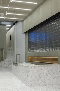 A modern reception desk made of concrete with glass inserts and a wooden counter.