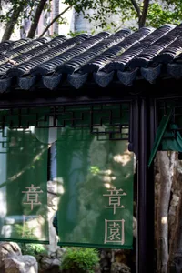 Green cloth with Chinese characters hanging from a traditional Chinese garden pavilion.
