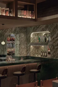 A modern industrial-style bar interior with a marble counter and stools.