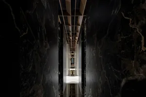 A corridor lined with dark marble walls, leading to a lobby or architectural space.