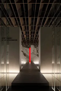 View down a minimalist hallway in an exhibition space, featuring stone walls.