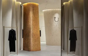 A modern fashion store with metallic columns and clothing racks.