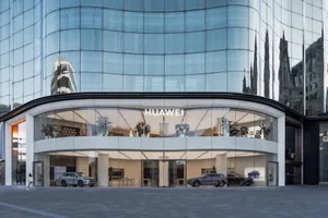 A modern Huawei storefront with a glass facade reflecting surrounding buildings.
