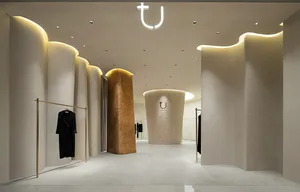Modern interior design of a clothing retail store featuring concrete, curved panels, and LED lighting