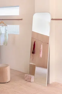 A clothing storage area with a wooden shelf and a mirror, featuring minimalist design elements.