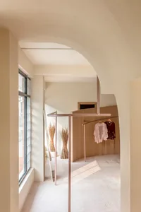 時尚精品店內，服裝懸掛在金屬衣架上，背景為木質牆面。