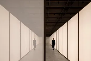 A minimalist corridor featuring glass walls and reflections.