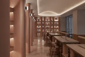 A modern cafe bar interior with wooden tables and stools, designed with a minimalist aesthetic.