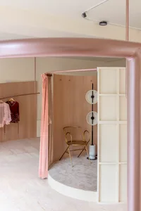 Modern fashion shop interior with metallic accents, featuring a velvet curtain, wooden walls, and a gold chair.