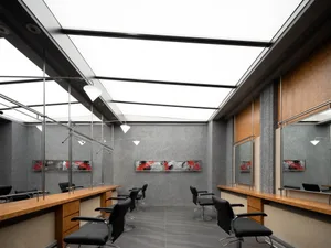 Modern, minimalist hair salon interior with metallic furniture and ceiling light panels.