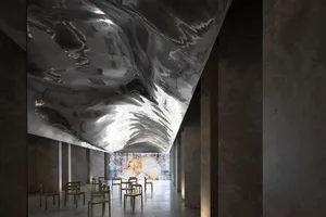 An interior space featuring a large, reflective black metal structure and modern furniture.