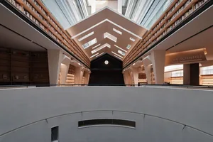 現代圖書館室內，設有混凝土柱、玻璃牆與金屬欄杆。