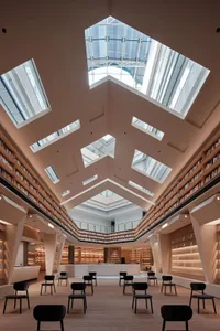 An indoor library with high ceilings, skylights, and wooden shelves filled with books.