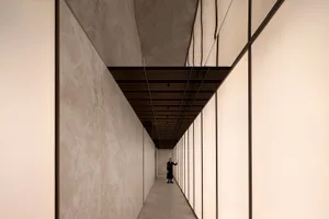 A modern minimalist corridor featuring glass panels and marble walls.