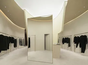 Minimalist fashion retail store with white reflective surfaces and neutral tones