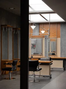 Modern interior of a barbershop featuring metal, wood, and glass materials