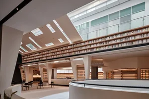 現代圖書館室內，混凝土牆面、玻璃欄杆，以及充滿書籍的眾多書架。
