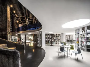 Industrial-style library with concrete and metal materials, featuring seating and bookshelves.