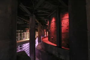 An industrial-style kitchen area with metallic walls and red lighting.