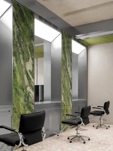 A hair salon with black chairs and green marble walls.