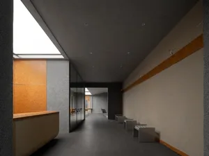 Modern, sleek hospital corridor with concrete walls and floor, geometric design, and natural light from skylights.