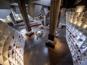 A modern library interior with concrete finishes and geometric bookshelves.