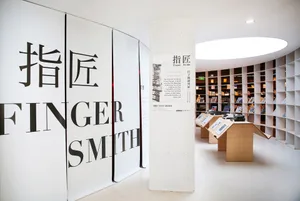Modern white-painted steel library interior with shelves filled with books, a central curved wall, and a light fixture at the