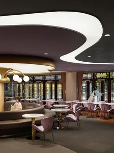 現代餐廳室內空間，搭配白金色燈具、紫色座椅，以及柔軟材質與玻璃隔間的混搭設計