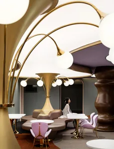 A modern restaurant interior featuring gold glass elements, metallic accents, and fabric seating