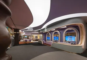 Interior view of a modern restaurant featuring metallic finishes, curved glass panels, and geometric shapes.