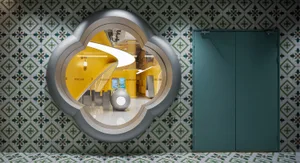 A retail space featuring a patterned tile wall with a large glass door and a yellow interior.