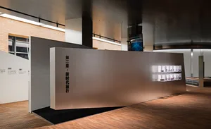 A modern exhibition space featuring a large metallic installation wall.