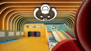 A vibrant, modern playroom with soft textiles and a colorful slide.
