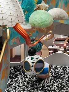 A whimsical, mixed-media installation featuring colorful, abstract shapes and textures in a playful space.