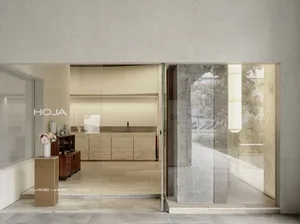 Interior of a modern coffee shop, featuring concrete walls and large glass windows.