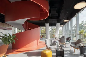 Modern industrial office reception area with red curved walls, white columns, glass walls, wooden furniture, potted plants, a