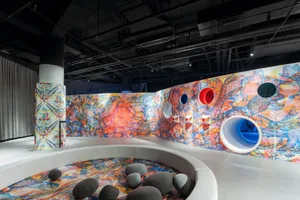 A modern installation featuring colorful painted sculptures and a circular seating area with stones.
