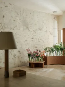 A modern interior space featuring a collection of flower arrangements displayed in various glass vases.
