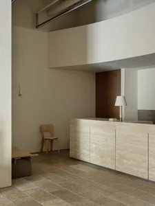 Modern lobby with minimalist design, featuring concrete elements and a sleek reception desk.